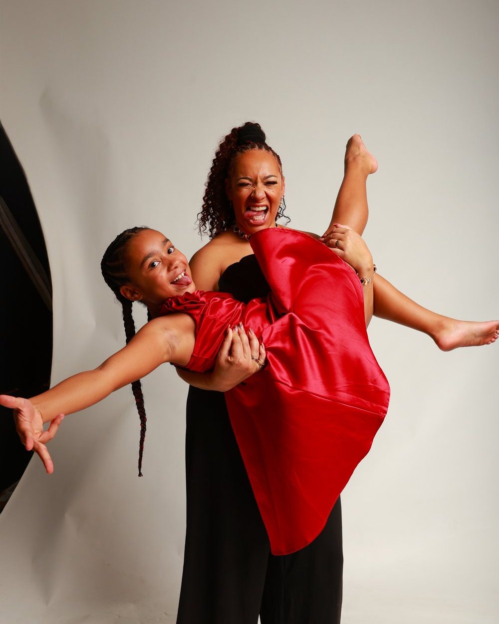 A Warriorz teacher lifting a student in a red dress, both laughing, at the awards night