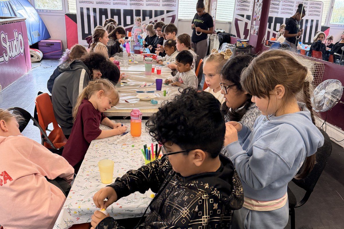 Children at a Warriorz holiday camp working at a craft table
